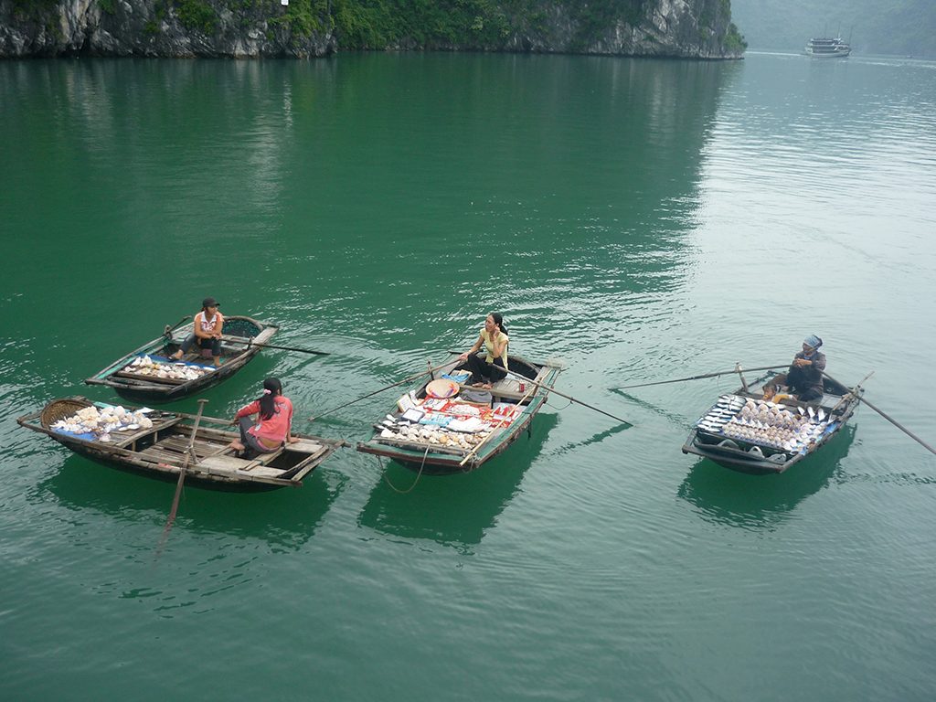 Souvenir sellers row to the tourist boats in Halong Bay, Vietnam 